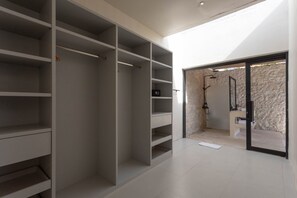 A modern interior with a large walk-in closet, a shower area with a stone wall, and a view of the outdoors. - Vega 2BR Luxury Private Pool Villa - Ungasan (South Kuta)