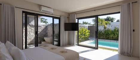 A modern bedroom with a large bed, a flat-screen TV, and a view of a swimming pool.