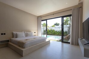 Camera moderna con un letto grande, una televisione e una porta scorrevole in vetro che dà su una zona piscina.