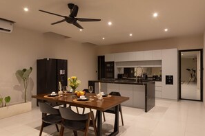 Una cucina moderna con isola centrale, zona pranzo con tavolo apparecchiato per quattro e ventilatore a soffitto.