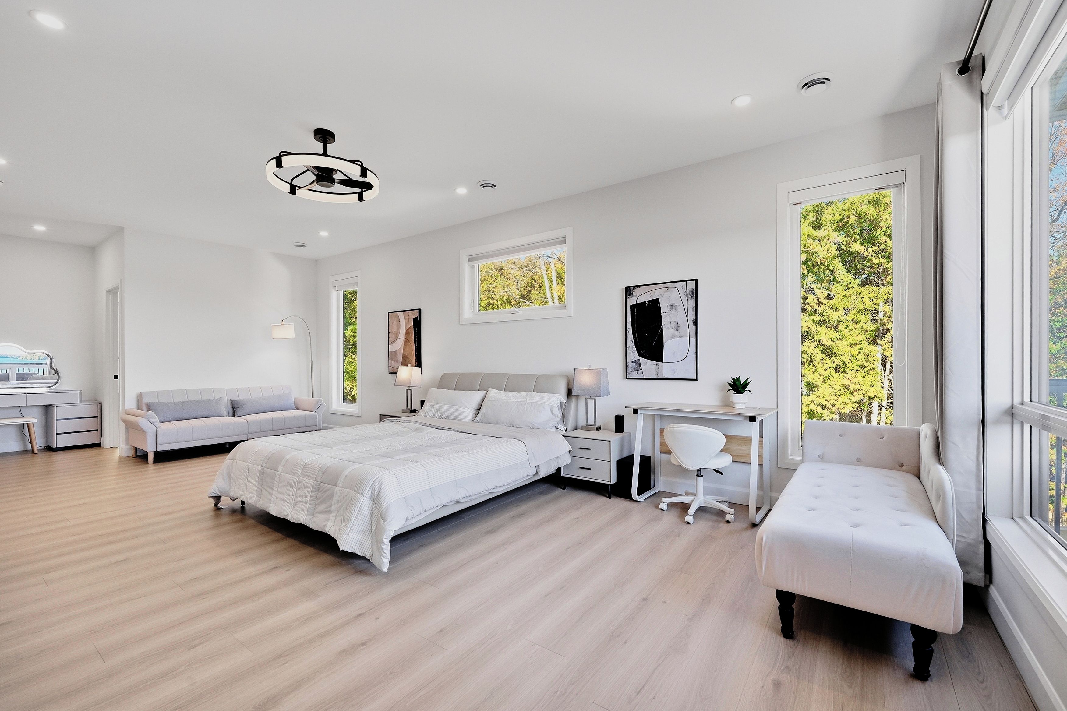 A modern bedroom with a bed, two sofas, a desk, and a chair.