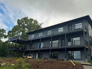 A multi-story building with balconies, large windows, and a covered outdoor area. - Newly Built Luxury 7BR Big Rideau Lake Cottage | Sleeps 20 (Rideau Lakes)