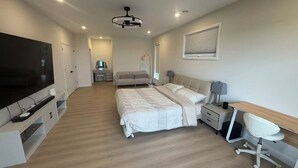 Une chambre moderne équipée d’un lit, d’un bureau, d’une chaise, d’un téléviseur et d’un luminaire au plafond.
