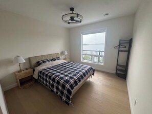 A bedroom with a bed, bedside lamps, a window with a view, and a ceiling fan.