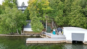 A dock extending into a body of water with a house in the background surrounded by trees.