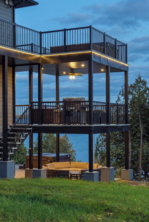 A multi-level outdoor deck with a covered seating area and a view of the water. - Newly Built Luxury 7BR Big Rideau Lake Cottage | Sleeps 20 (Rideau Lakes)