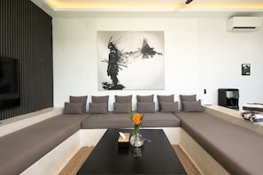 A modern living room with a sectional sofa, a coffee table, and a large abstract painting on the wall. - Marea 2BR Luxury Private Pool Villa - Uluwatu (South Kuta)