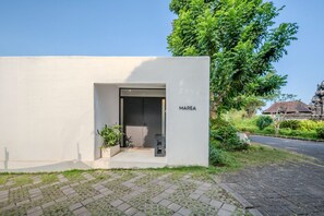 A modern building with a minimalist design, a nameplate reading 'MAREA,' and a paved entrance area with potted plants. - Marea 2BR Luxury Private Pool Villa - Uluwatu (South Kuta)
