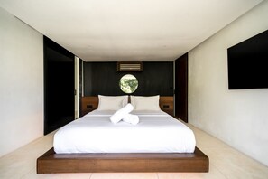 Ein modernes Hotelzimmer mit einem großen Bett, einem runden Spiegel und einem an der Wand befestigten Fernseher.
