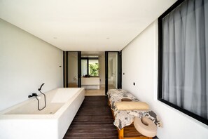 A modern bathroom with a bathtub, a small bedside table, and a window. - Brezza 3BR Luxury Private Pool Villa - Uluwatu (South Kuta)