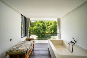 Ein modernes Badezimmer mit einer großen Badewanne, einer kleinen Holzbank und Blick auf üppiges Grün.