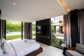 A modern bedroom with a large bed, a TV, and a view of a swimming pool. - Brezza 3BR Luxury Private Pool Villa - Uluwatu (South Kuta)