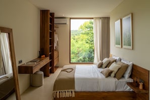 A bedroom with a large bed, a desk, and a wardrobe. There is a window with a view of greenery. - Majo 1BR Romantic Villa, 3 Min to Thomas Beach (South Kuta)
