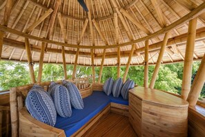 A circular wooden structure with a thatched roof, seating with patterned cushions, and a view of greenery outside. - Ahura 5BR Oceanview in Bingin Uluwatu (Kecamatan Kuta Selatan)