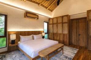 Une chambre à coucher avec un grand lit, des tables de chevet, un banc, une armoire et un ventilateur de plafond.