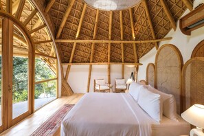 A room with a high, thatched roof, a bed with white linens, two chairs, and a small table. - Ahura 5BR Oceanview in Bingin Uluwatu (Kecamatan Kuta Selatan)