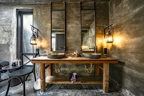 Ein rustikales Badezimmer mit einem Holzbadezimmer-Möbel, zwei runden Waschbecken und einem großen Spiegel.