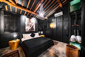 Ein modernes Schlafzimmer mit einem großen Bett, Holzbalken an der Decke, einer Kristallleuchter und einem großen gerahmten Bild an der Wand.