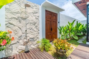 A modern house with a stone wall, a wooden door, and a garden with tropical plants. - Villa Sofra 2BR Private Pool, 350mbps WiFi- Bingin (South Kuta)