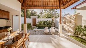 A modern outdoor dining area with a wooden pergola, a pool, and a stone wall. - Parisula 1BR Villa with Pool in Bingin Uluwatu (South Kuta)