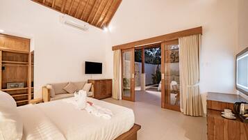 A spacious bedroom with a large bed, wooden wardrobe, a flat-screen TV, and a sliding glass door leading to an outdoor area.