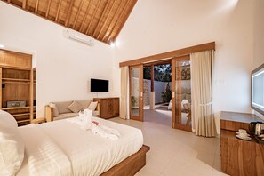 A spacious bedroom with a large bed, wooden wardrobe, a flat-screen TV, and a sliding glass door leading to an outdoor area.