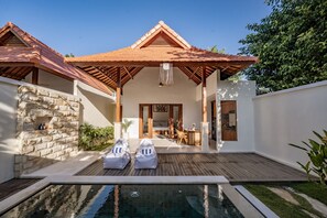 A modern villa with a swimming pool, stone walls, and a wooden deck.