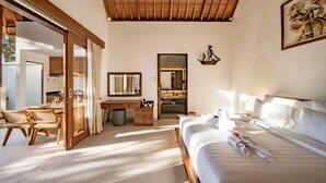 A well-lit bedroom with a large bed, a wooden desk, a mirror, and a bathroom visible through an open door. - Parisula 1BR Villa with Pool in Bingin Uluwatu (South Kuta)