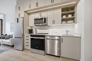 Eine moderne Küche mit Edelstahlgeräten, inklusive Backofen, Mikrowelle und Geschirrspüler, sowie einer weißen Arbeitsplatte.