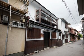 Un bâtiment japonais traditionnel, doté d’une façade en bois, d’une entrée bien visible et d’une enseigne indiquant qu’il s’agit d’un établissement commercial.