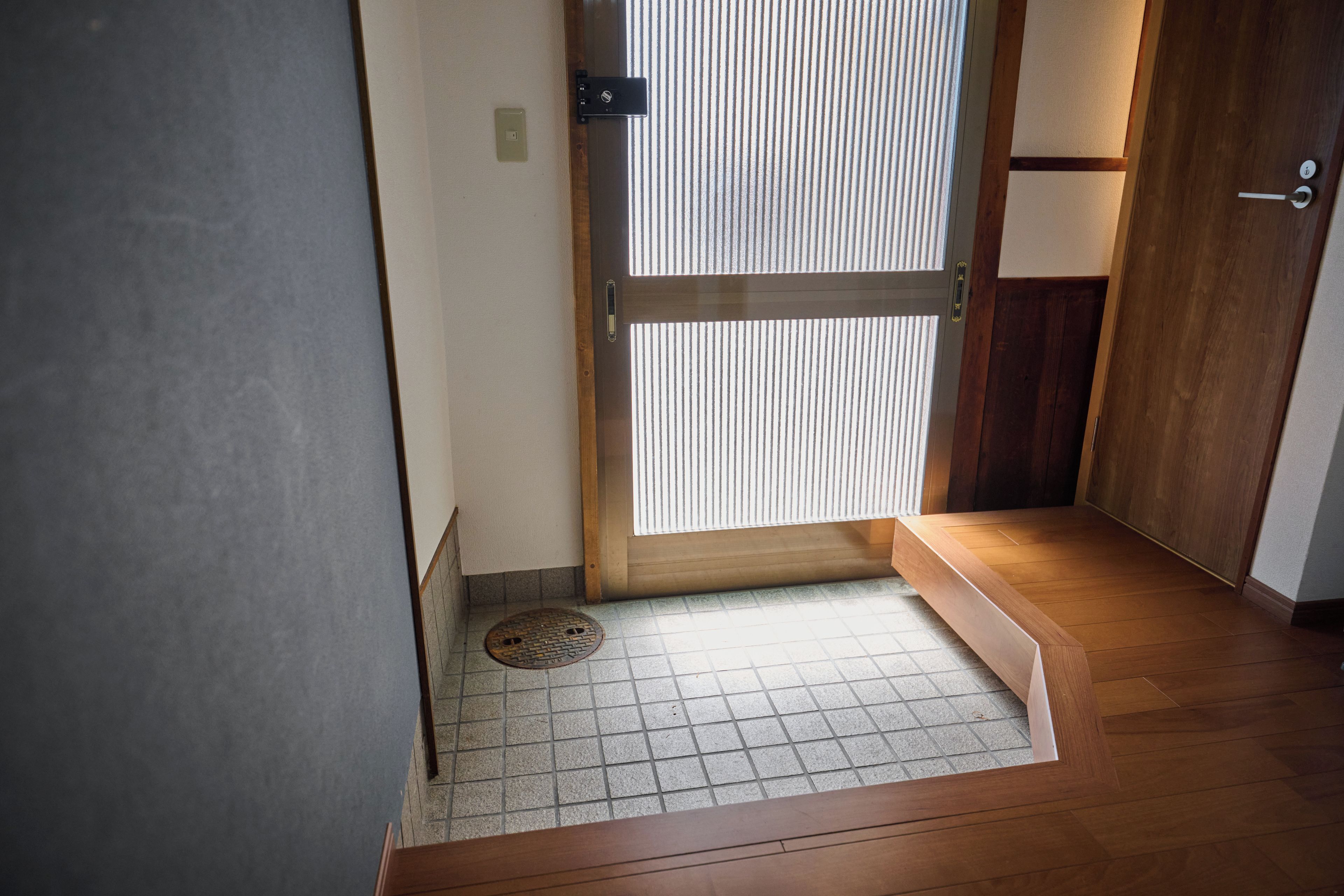 A wooden door with a sliding glass panel, a tiled floor, and a small step leading to a wooden threshold.