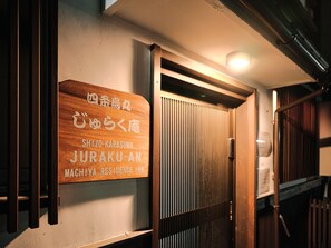 Ein Holzschild mit japanischem Text, das den Namen eines Hotels angibt.