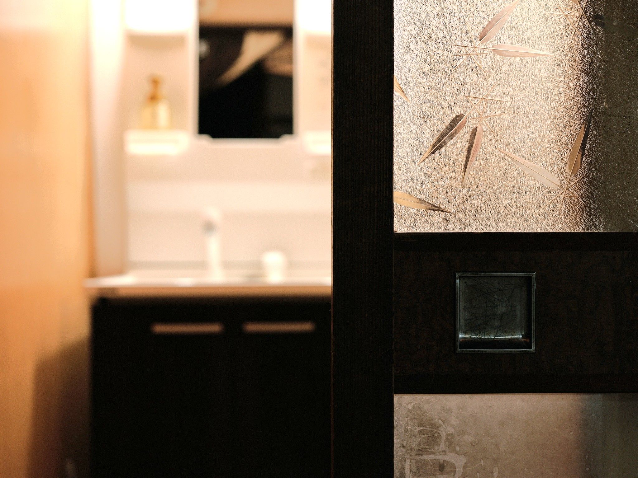 Baño con lavamanos, espejo y pared con textura.