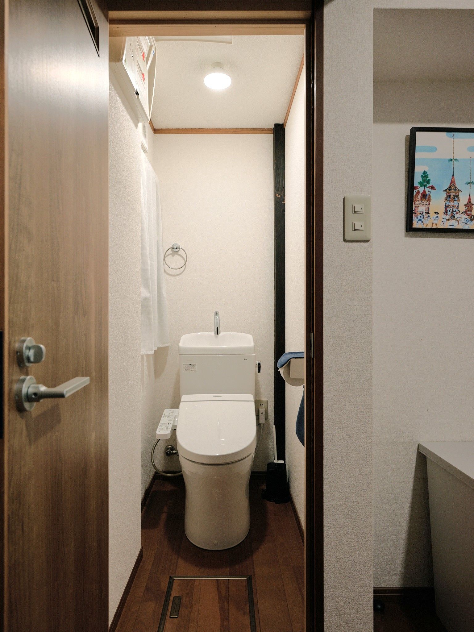 A compact bathroom with a toilet, sink, and a small towel rack.