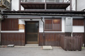 Ein Gebäude mit Holzfassade, einem Metallgitter und einem Schild, das es als Wohnhaus kennzeichnet.