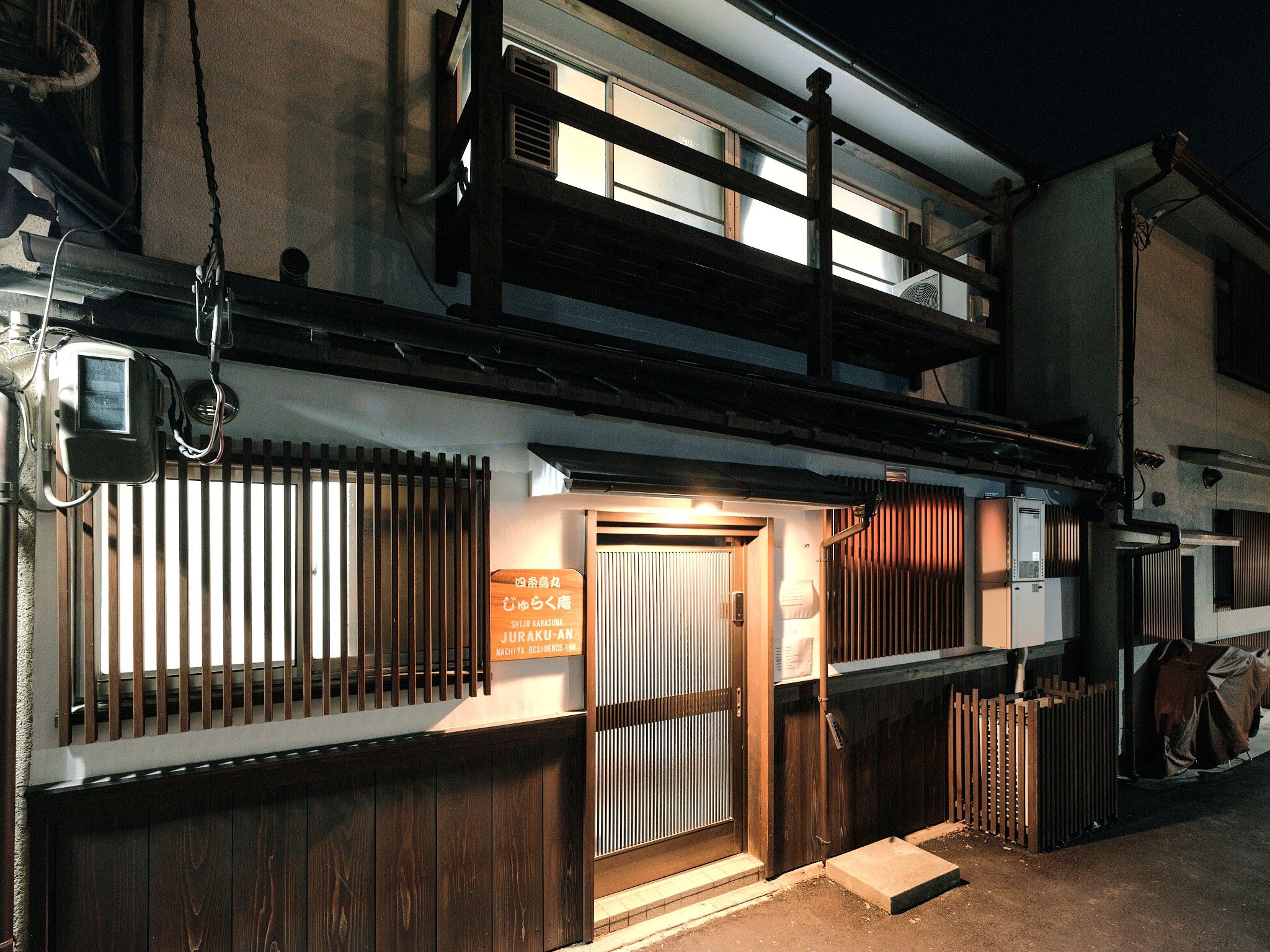 A two-story building with a wooden facade, a visible entrance, and a sign indicating it is a residence.