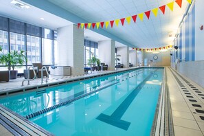 An indoor swimming pool with clear lane dividers, a clock on the wall, and potted plants around the pool area. - Blueground | New Eastside, jacuzzi, nr Millennium Park (Chicago)