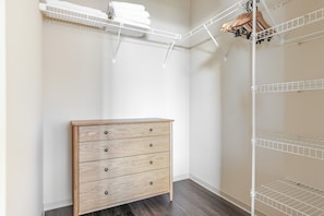 A room with a wooden dresser, white shelving units, and a hanging shoe rack. - Blueground | New Eastside, jacuzzi, nr Millennium Park (Chicago)