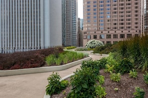 A landscaped garden area with various plants and a pathway, surrounded by tall buildings. - Blueground | New Eastside, jacuzzi, nr Millennium Park (Chicago)