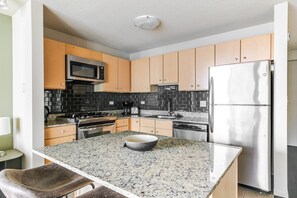 A modern kitchen with granite countertops, stainless steel appliances, and wooden cabinets. - Blueground | New Eastside, jacuzzi, nr Grant Park (Chicago)