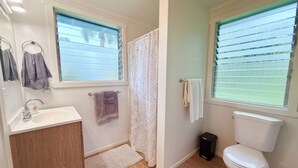 A bathroom with a sink, toilet, and shower curtain. - Private Gated Tropical Cottage Near Hilo & Pāhoa –Peaceful, Secure Island Escape (Keaau)