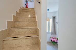 A marble staircase leading to a landing with a fire extinguisher mounted on the wall. - New & Panoramic Harbor Views - Sanciolu House (Sciacca)