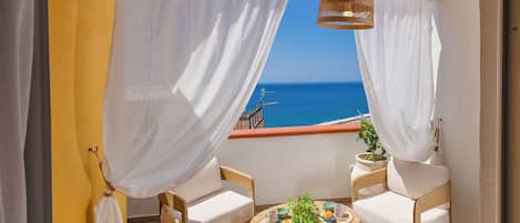 Un balcon avec deux chaises, une table et un luminaire suspendu.