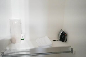 A bathroom with a towel, a white container, and a black device on a shelf.