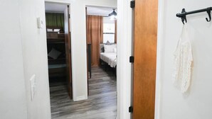Corredor que dá para um quarto, com uma cama, um armário e um porta-toalhas.