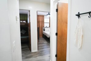 A hallway leading to a bedroom with a bed, a closet, and a hanging towel rack. - ModWest Escape | Pets Welcome | Near I-40 & Rt 66 (Weatherford)