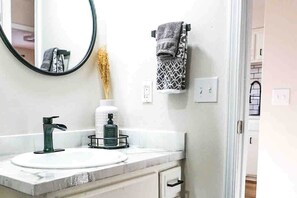 A bathroom with a white sink, a black faucet, a mirror, and a towel rack with a patterned towel.