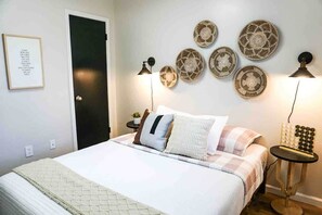 A bedroom with a bed, bedside tables, wall-mounted lamps, and decorative plates.