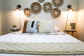 A neatly made bed with a quilted bedspread, a variety of pillows, and two bedside lamps.