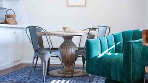 A dining area with a round table, four chairs, a teal sofa, and a framed botanical print on the wall. - Colorful Retreat | Near I-40 &SWOSU | Pets Welcome (Weatherford)
